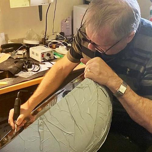 John Dearden in his workshop hand engraving the inner rim of a large decorated stainless steel champagne bowl