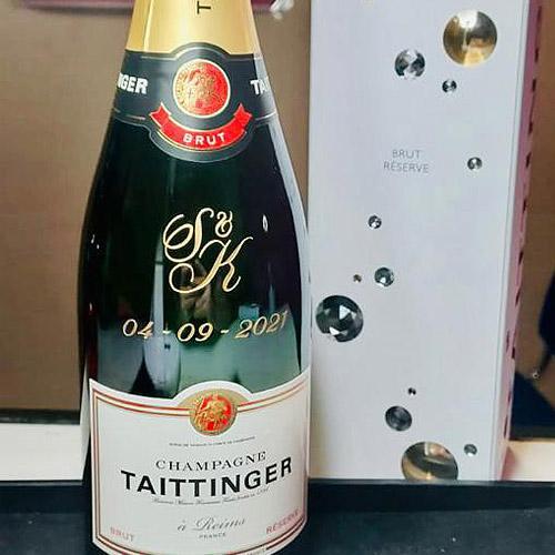 A bottle of Taittinger champagne with machine inscribed monogram initials S & K along with a date