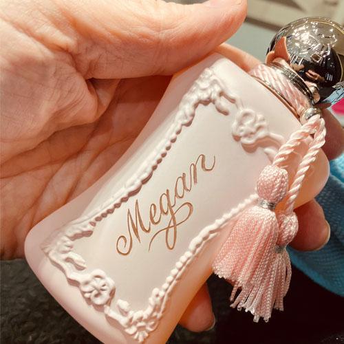 Ornate pink bottle of Parfum de Marly hand engraved in a flowing script with the name Megan