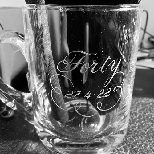 Hand engraved glass tankard in a flowing script font the word Forty and a date