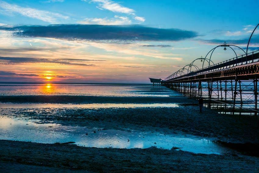 The ornate iron structure of Southport pier just catching the sun as it sets over the Irish Sea on a winter's day